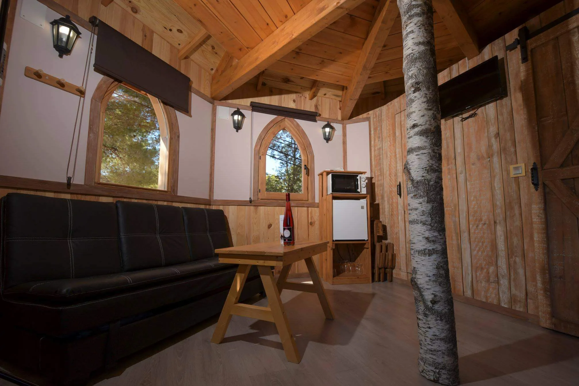 interior de la cabaña en el árbol del valle del cabriel con sofá, mesa de madera y detalles rústicos