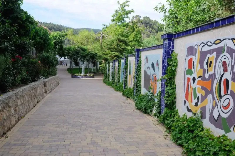 pasillo exterior decorado con murales y vegetación en el balneario de la concepción y cabañas valle del cabriel