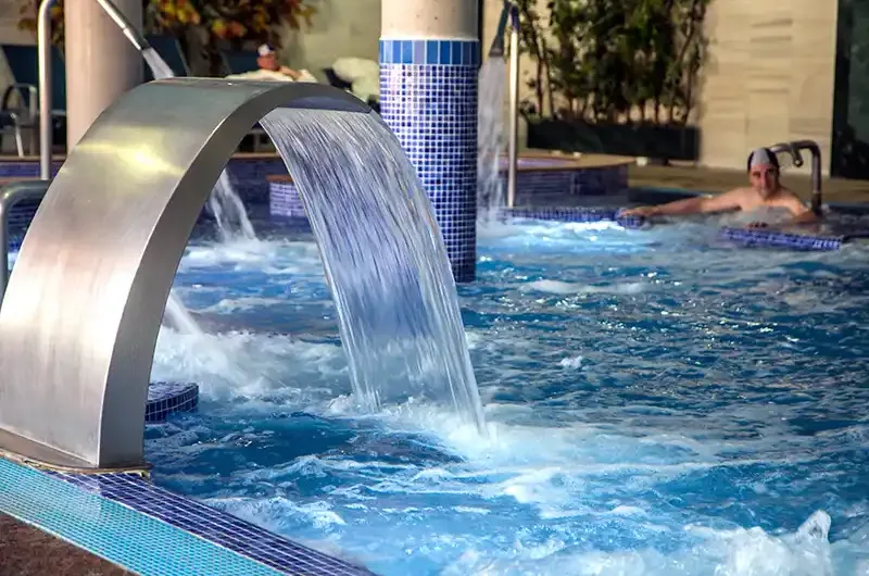 chorro de agua en piscina termal con zona de relax en el balneario de la concepción y cabañas valle del cabriel