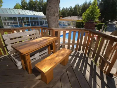 terraza de madera con mesa rústica y vistas a la piscina en las cabañas rurales valle del cabriel