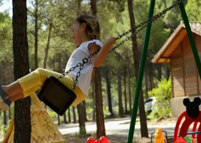 niña jugando en columpio en zona infantil de cabañas rurales valle del cabriel rodeada de naturaleza