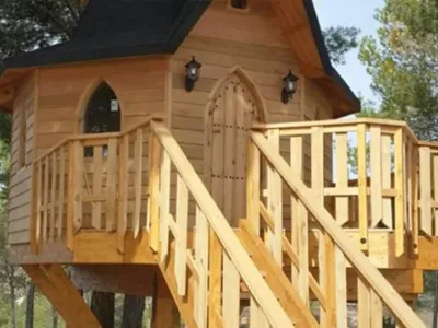 cabaña de madera elevada tipo casa del árbol con escaleras y barandilla en entorno natural