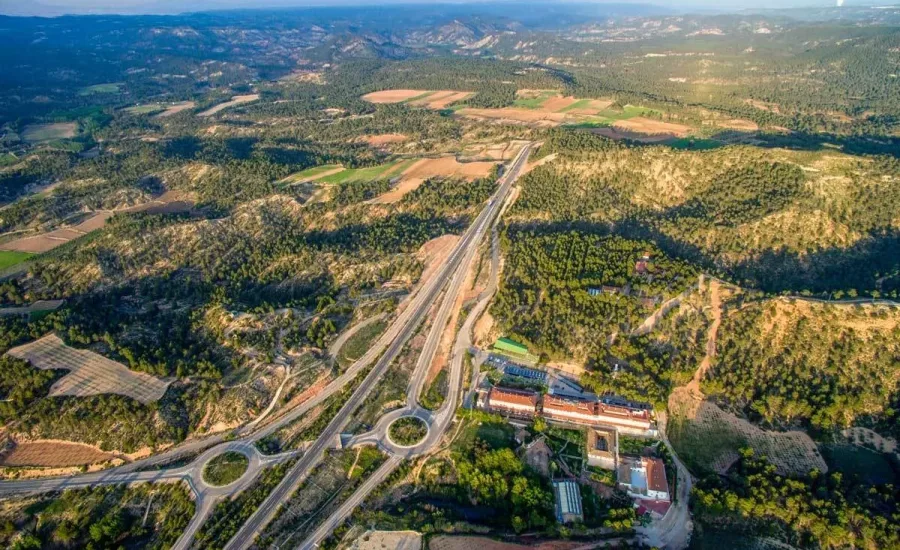 panorámica aérea del balneario de la concepción junto a la autovía, rodeado de montañas y campos en el valle del cabriel
